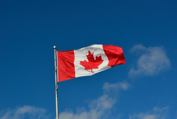The Canadian flag soaring high against the blue sky