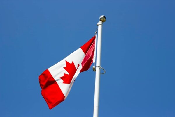 A Canadian flag against a bright blue sky
